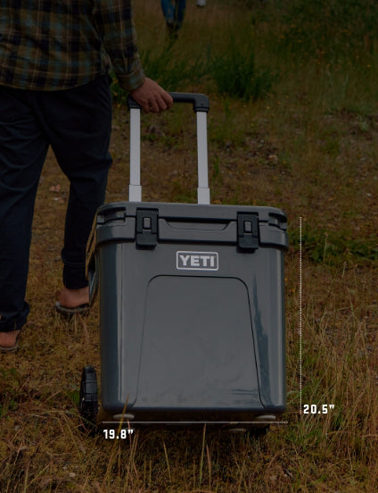 Person holding a YETI cooler in a grassy outdoor setting