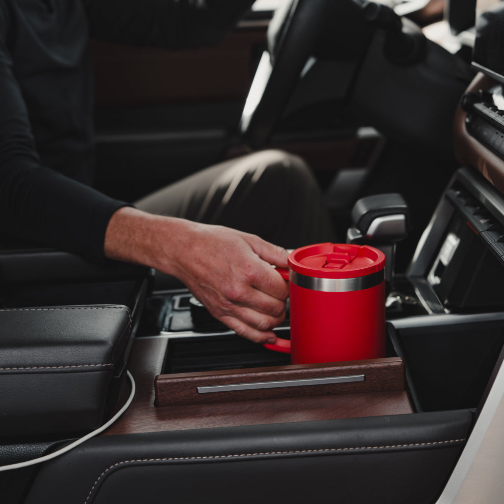 Person placing a red Rambler Travel Straw Mug into a car's cup holder.