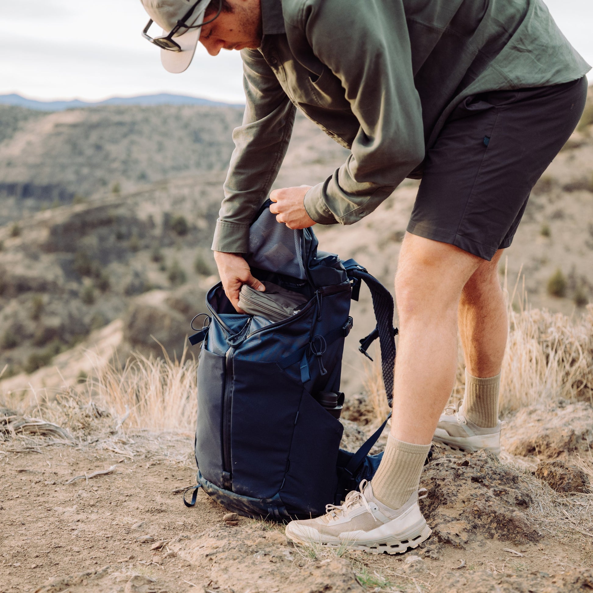 Person in outdoor setting with backpack and mountains in the background