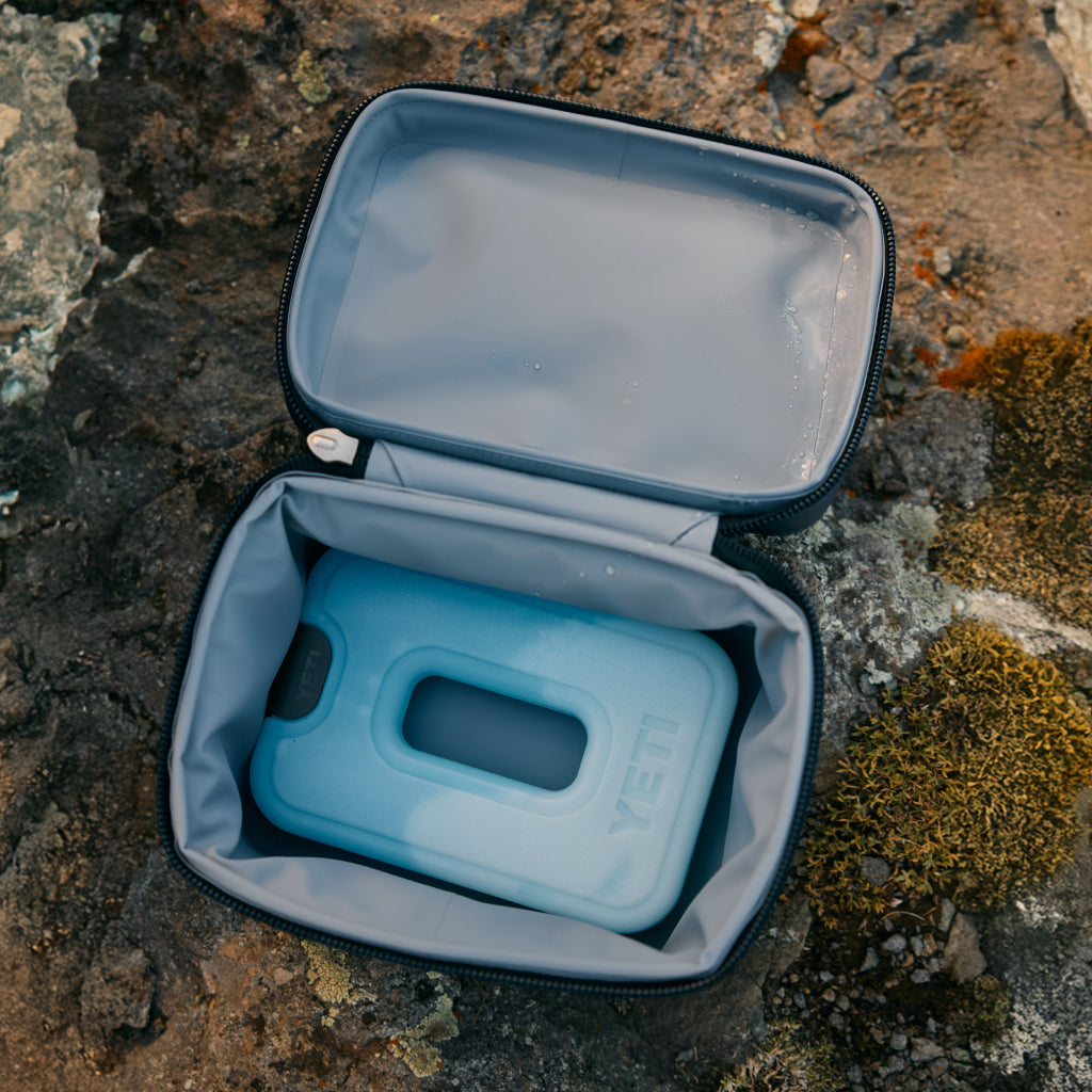 Blue Yeti cooler bag inside an open gray carrying case on a rocky surface