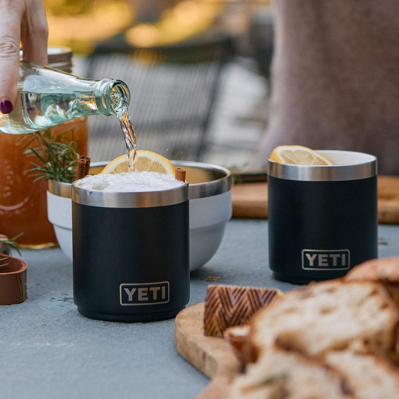 Person pouring a drink into a YETI insulated cup outdoors.
