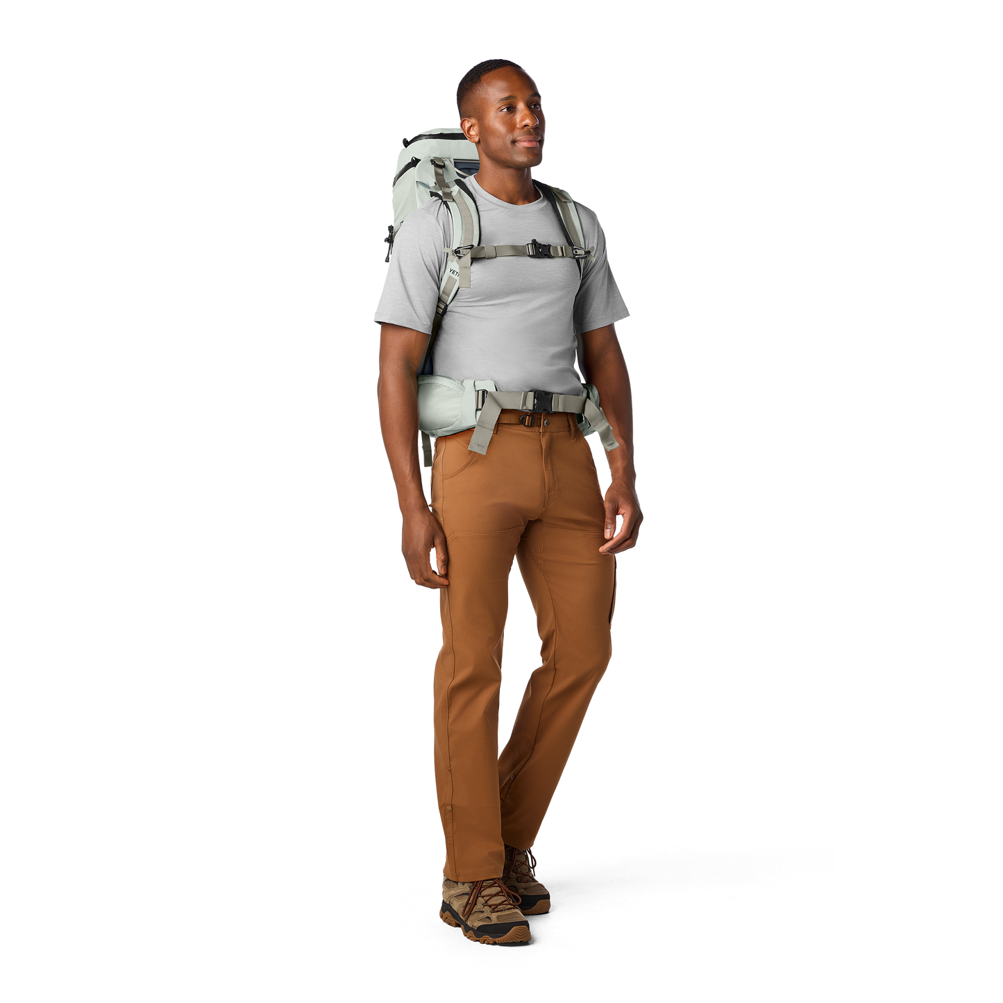 Person wearing a hiking backpack and brown trousers on a white background