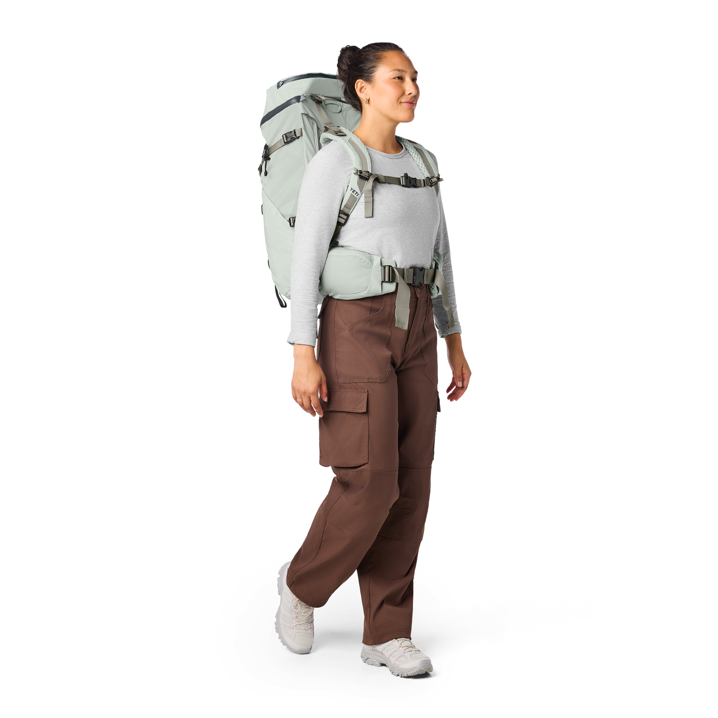 Person wearing a large backpack and brown pants on a white background