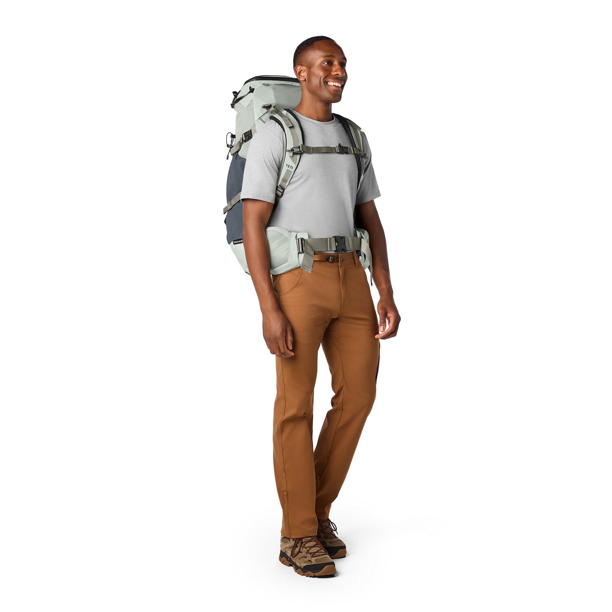 Man wearing a hiking backpack and brown trousers on a white background